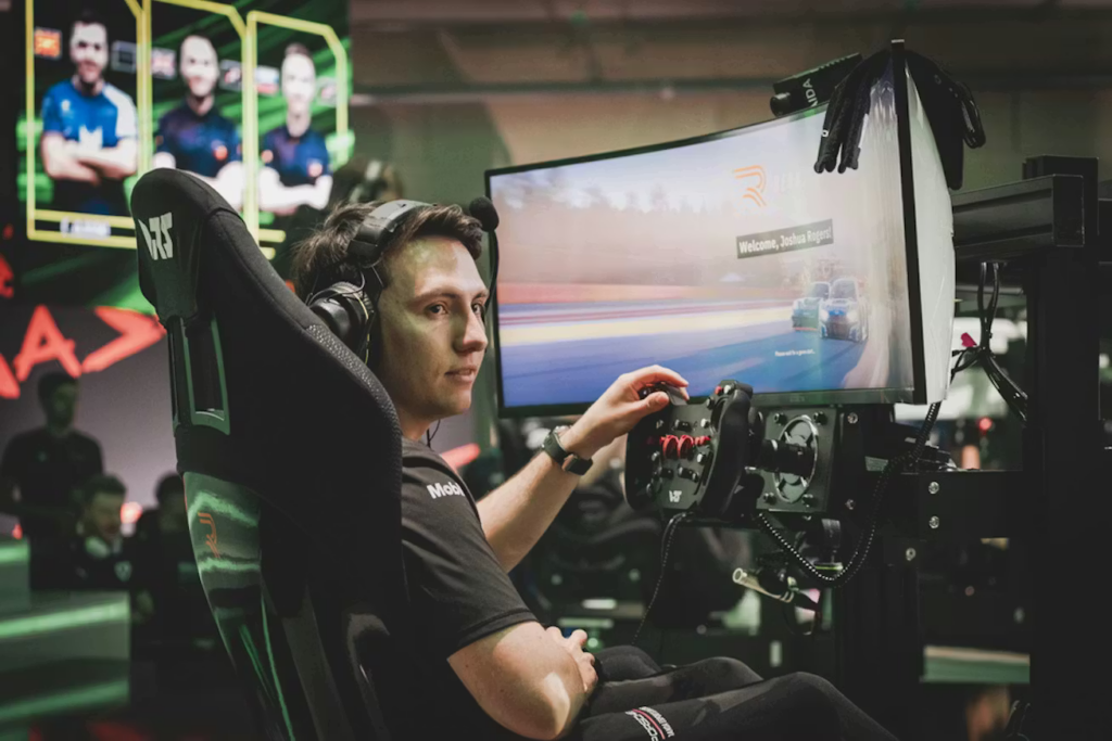 Simracer sitzt im Racing-Cockpit vor einem Curved-Monitor